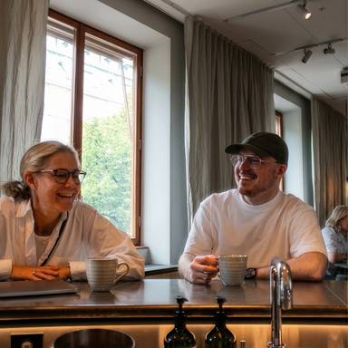 Two colleagues sitting in an espresso bar laughing.
