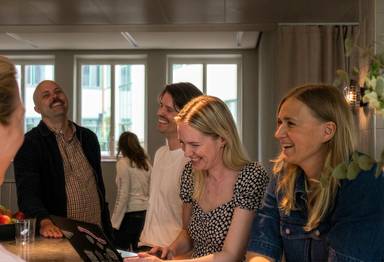 Colleagues laughing together at the office espresso bar.